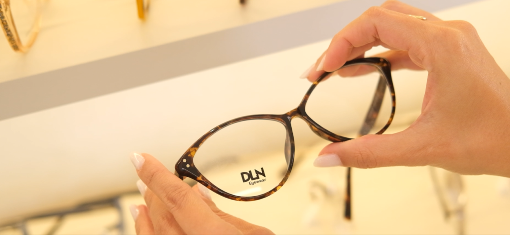 Armação de óculos da marca própria DLN Eyewear, sendo apresentada por uma vendedora da Óticas Dellane