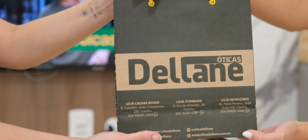 Sacola personalizada da Óticas Dellane, com o logo da marca e endereços das lojas de Caldas Novas, Itumbiara e Patrocínio